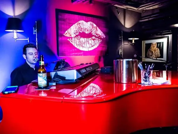 Piano bar setup with a grand piano under red neon