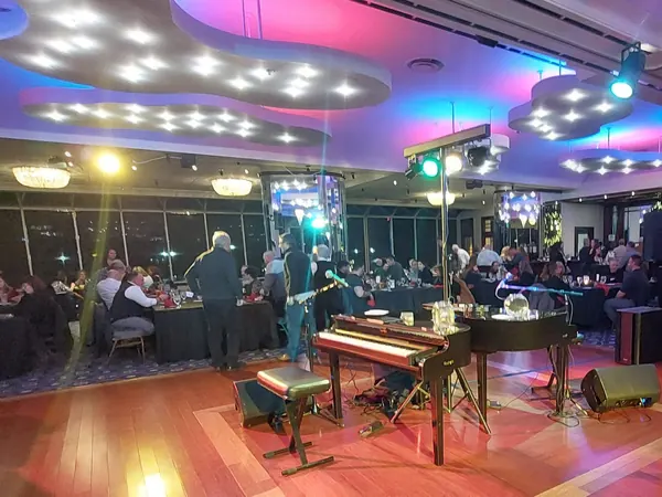 Two grand pianos set on a corporate event stage lit red in a Michigan ballroom