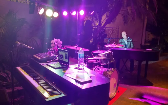 Dueling piano band on a stage under purple and gold lights
