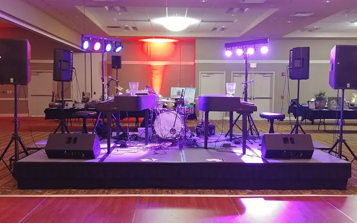 Dueling pianos with drum kit set up on a ballroom stage