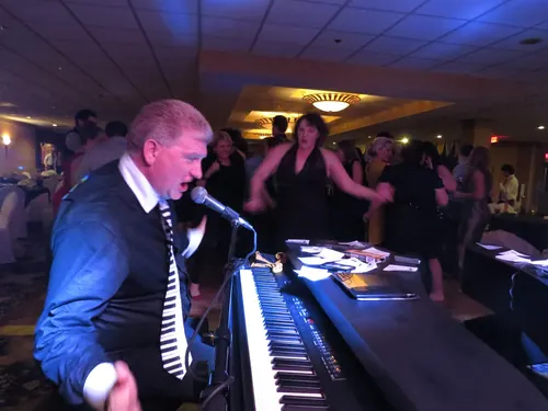 Piano player singing to the crowd at a wedding reception