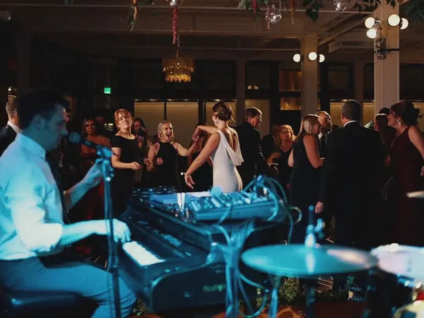 Dueling pianos at a wedding reception, bride and guests singing along in Michigan